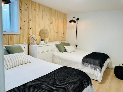 two beds in a bedroom with wooden walls at Pavillon de jardin Neuf Baie de Tadoussac Clim Parking - 2 chambres in Tadoussac