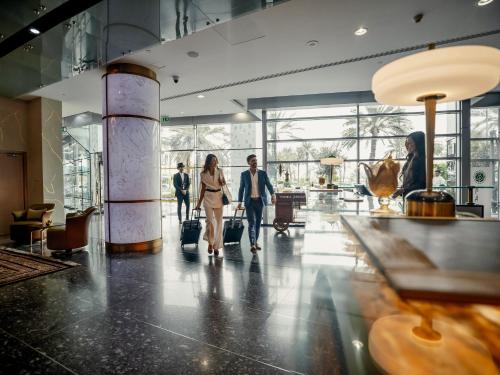 personas caminando por el vestíbulo del aeropuerto con su equipaje en Golden Sands Boutique Hotel-Dubai Creek, en Dubái