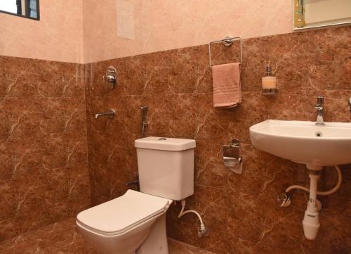 a bathroom with a toilet and a sink at Ranghavi sands Apartment with Pool - near beach and Dabolim Airport in Bogmolo