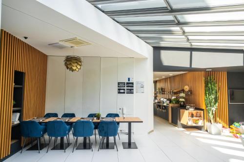 a dining room with a table and blue chairs at Hotel Plzeň in Plzeň