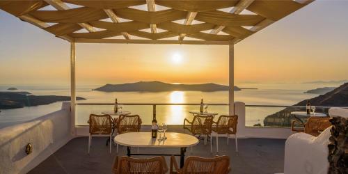 a restaurant with tables and chairs and a view of the ocean at Vallas Apartments & Villas in Firostefani