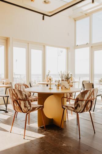 a table and chairs in a room with windows at Strandhuisjes Zoomers aan Zee in Castricum