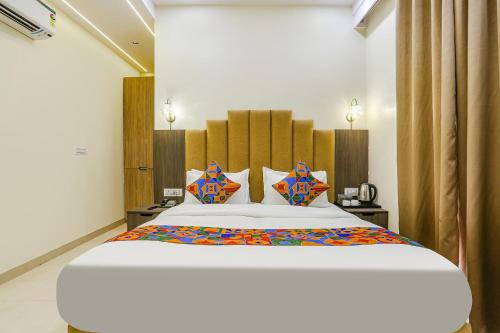 a bedroom with a large white bed with colorful pillows at FabHotel Vishesh Villas in New Delhi