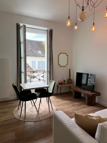 a living room with a table and a window at Le Laurencin Sens - Le Campagne in Sens