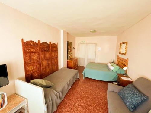 Pensión las Hojas في توذيلا: غرفة معيشة بها سريرين وأريكة