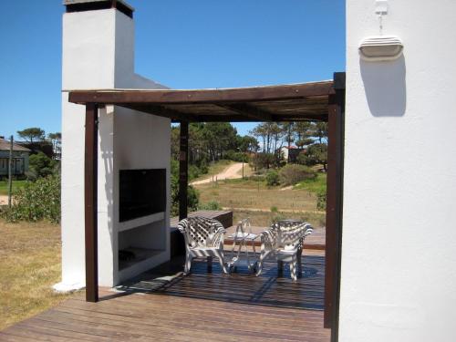 2 sillas y una mesa en una terraza de madera en Casa de Familia Jiro, en Punta del Diablo