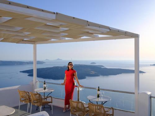 a woman in a red dress standing on a balcony at Vallas Apartments & Villas in Firostefani