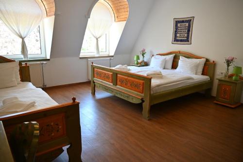 a bedroom with two beds and two windows at Székely Kúria in Miskolctapolca