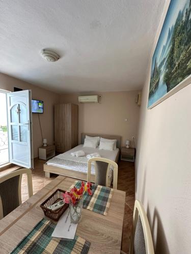 Apartman Nina في ريسان: غرفة بها سرير وطاولة عليها زهور