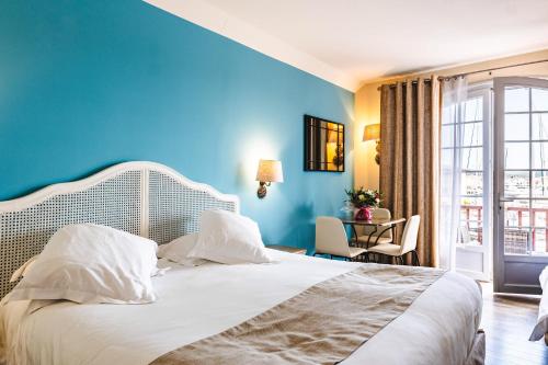 a bedroom with a white bed with a blue wall at Le Suffren Hôtel in Grimaud
