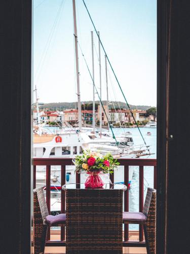 a table with a vase of flowers on a balcony with a boat at Le Suffren Hôtel in Grimaud