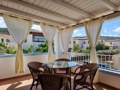 een patio met een tafel en stoelen op een balkon bij Residenze S'ABBAIDA in Tanaunella