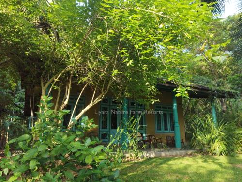 een huis met een boom ervoor bij Liyara Nature Farm Resort in Gampaha