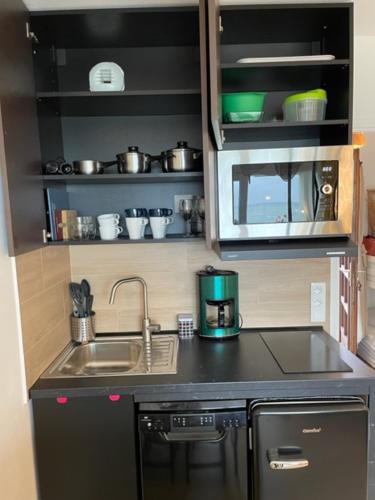 une petite cuisine avec un évier et un micro-ondes dans l'établissement FACE À LA PLAGE Terrasse-Parking-Wifi-Draps et Serviettes, à Hendaye