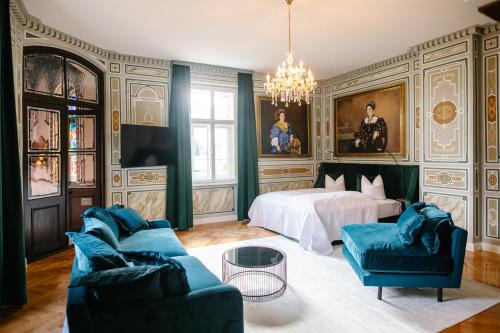 a bedroom with a bed and a couch and chairs at Georgi Schloss - Boutique Hotel in Ehrenhausen