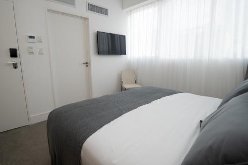 a bedroom with a bed and a tv on the wall at Vain Boutique Hotel in Buenos Aires