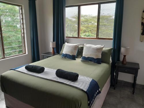 een slaapkamer met een groot bed met 2 kussens erop bij African Thistle in St Lucia