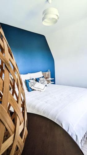 un lit avec une tête de lit bleue et deux chaises en bois dans l'établissement La Brise du Clos , Grand 3 pièces, Piscine & Tennis, à Villers-sur-Mer