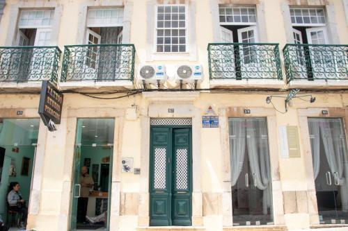 a building with a green door and a balcony at Blife Alicya private rooms in Faro