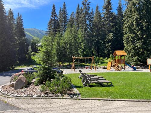 um parque com um banco e um parque infantil em Hotel Mikulášska Chata em Demanovska Dolina