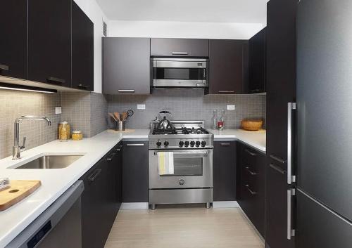 a kitchen with black cabinets and a stainless steel stove at Unique Place in midtown NYC in New York