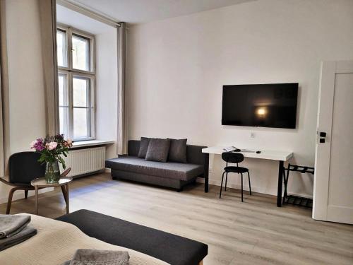 sala de estar con sofá y escritorio con TV en Anny 5 Apartamenty en Cracovia