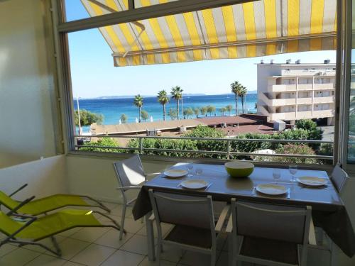- une salle à manger avec une table et des chaises et une vue sur l'océan dans l'établissement Appartement T2 au 2e étage sans ascenseur: Terrasse, TV, lave-vaisselle, wifi en option - FR-1-308-197, au Lavandou