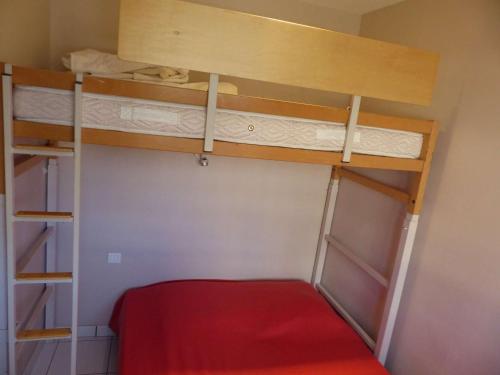 Cette petite chambre comprend 2 lits superposés avec des draps rouges. dans l'établissement Appartement T2 au 2e étage sans ascenseur: Terrasse, TV, lave-vaisselle, wifi en option - FR-1-308-197, au Lavandou