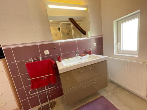 une salle de bain avec un lavabo et une serviette rouge dans l'établissement Gîte rénové 2024 calme et proche du centre, tout inclus, équipé et confortable, idéal pour découvrir Amboise - FR-1-381-580, à Amboise