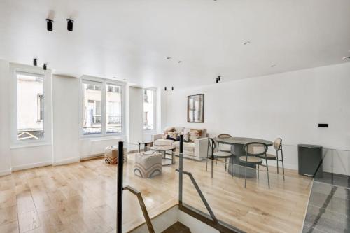 Cette grande chambre blanche dispose d'une table et de chaises. dans l'établissement Branché Luxueux et Moderne - Réaumur-Sébastopol, à Paris