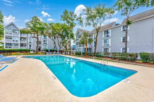 a swimming pool in front of a building with trees at 2BR/2BA Condo at Arcadian Dunes Building 10-238 in Myrtle Beach
