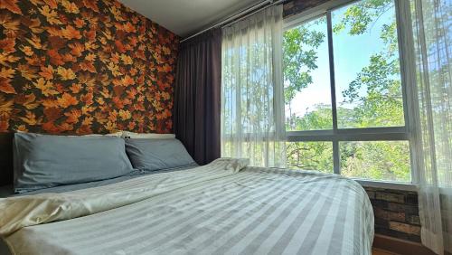a bedroom with a bed and a large window at Plus 2 Condo Phuket by ABCD in Kathu