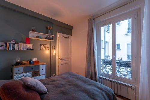 une chambre avec un lit et une grande fenêtre dans l'établissement Appartement parisien (12ème), à Paris