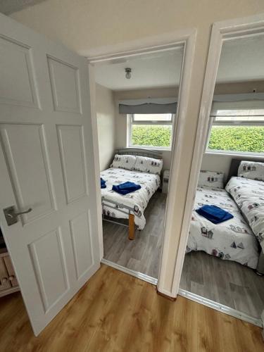 two beds in a room with two windows and a door at Hillview 1st floor apartment in Brean