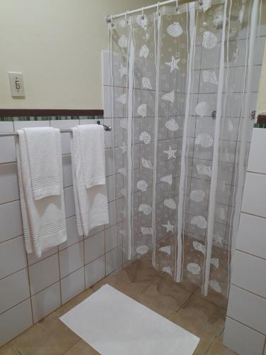 a bathroom with a shower curtain with fishes and towels at Pousada Dos Cajueiros in Paripueira
