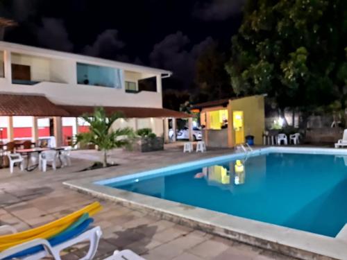 a villa with a swimming pool at night at Pousada Dos Cajueiros in Paripueira