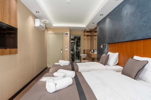 Habitación con 3 camas y toallas blancas. en Marlon Hotel en Estambul
