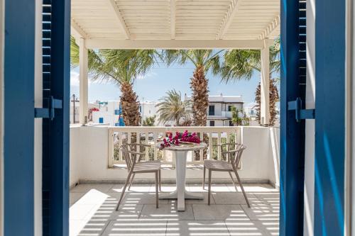a table and chairs on a balcony with palm trees at Hotel Francesca in Agios Prokopios