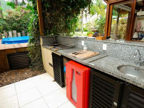 Casa Espetacular com Jacuzzi Churrasqueira e WIFI في ساو سيباستياو: طاولة مطبخ مع حوض ومبرد احمر