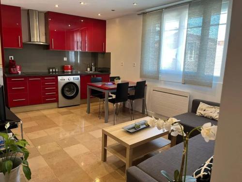 - une cuisine et un salon avec des armoires rouges et une table dans l'établissement Appartement moderne à Aubervilliers - 45 m² - Parking payant, à Aubervilliers