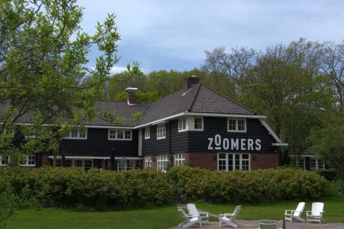 a large black house with white chairs in front of it at Zoomers aan het Bos in Castricum