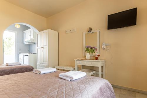 a bedroom with two beds and a television on the wall at Hotel Francesca in Agios Prokopios