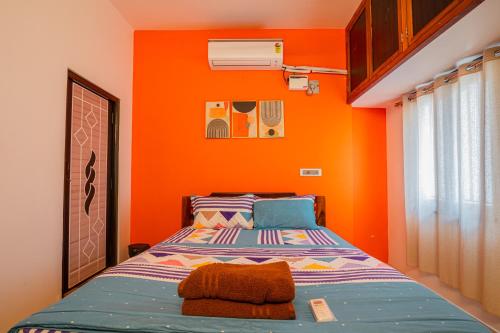 ポンディシェリにあるMaison Annaiのオレンジ色の壁のベッドルーム1室、ベッド1台が備わります。