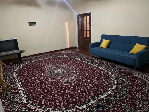 ein Wohnzimmer mit einem blauen Sofa und einem Teppich in der Unterkunft Юнусабад 13 корзинка 