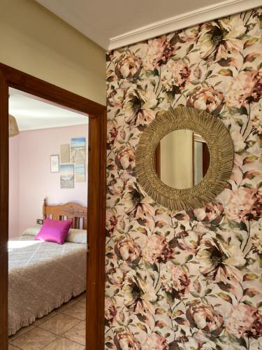 a bedroom with a flowery wall with a mirror at El Hoyaco in Los Espejos de la Reina