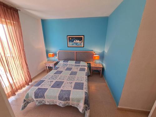 1 dormitorio con 2 camas y pared azul en Apartamentos Ágata V.v., en La Manga del Mar Menor