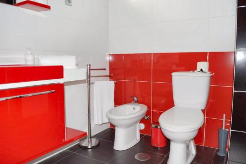 a red bathroom with a toilet and a sink at One bedroom apartement with sea view balcony and wifi at Ribeira Grande in Ribeira Grande
