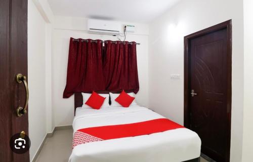 a bed with red pillows in a room at Hotel Prakrathi Residency in Bangalore