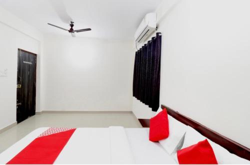 a bedroom with a white bed with red pillows at Hotel Prakrathi Residency in Bangalore