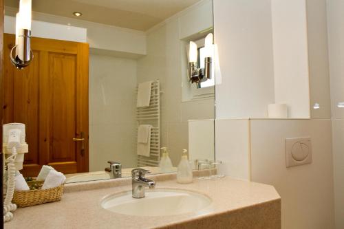 ein Bad mit einem Waschbecken und einem Spiegel in der Unterkunft Gasthof-Hotel Bramosen in Weyregg